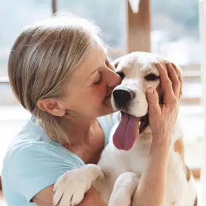 woman with dog in embrace - CT Shoreline - How Dogs Enhance Our Health and Happiness