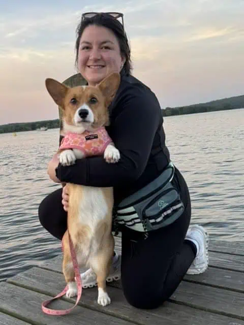 Adriana, founder of Shoreline Happy Paws, with her Corgi Cannoli on the Connecticut Shoreline at sunset
